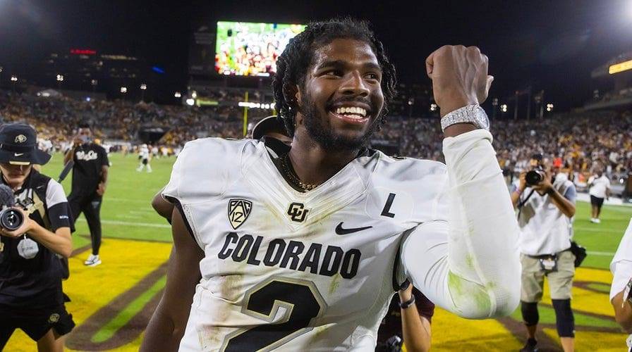 Colorado football player wearing a white jersey with the number 2, smiling and raising a fist in celebration on the field.